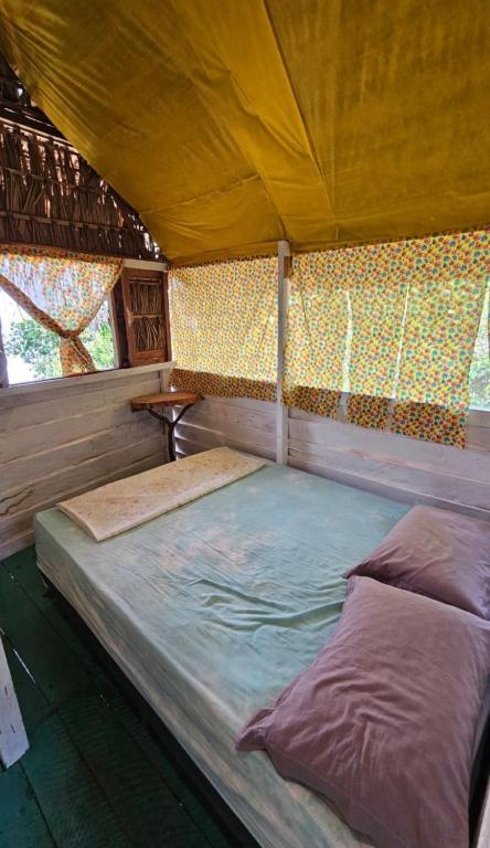 an empty bed in a tent with windows at A Casa Da Ilha Cotijuba in Belém