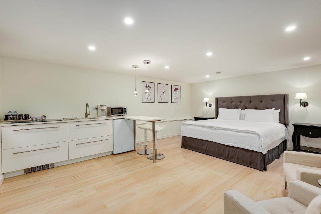 a white bedroom with a bed and a kitchen at Classic King Size Guest Suite with AC in Burnaby