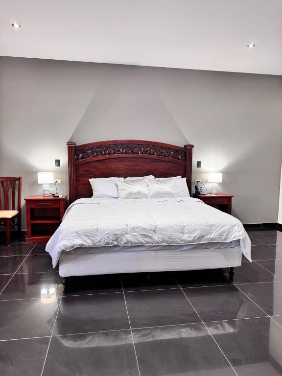 a bedroom with a large white bed with two night stands at Hotel Rubinos in San Salvador