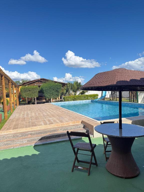 a table with a chair and an umbrella next to a pool at Hotel pousada Xique Xique in Piranhas