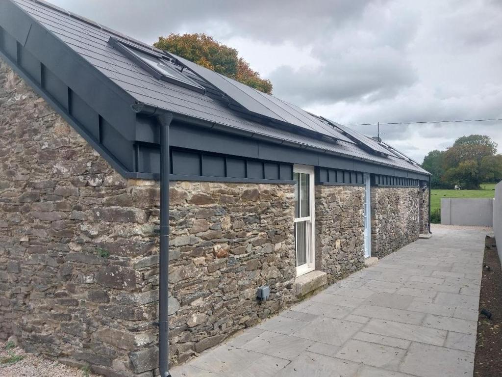 a stone building with a metal roof on it at Lil's Cottage, Grangecon in Grange Con