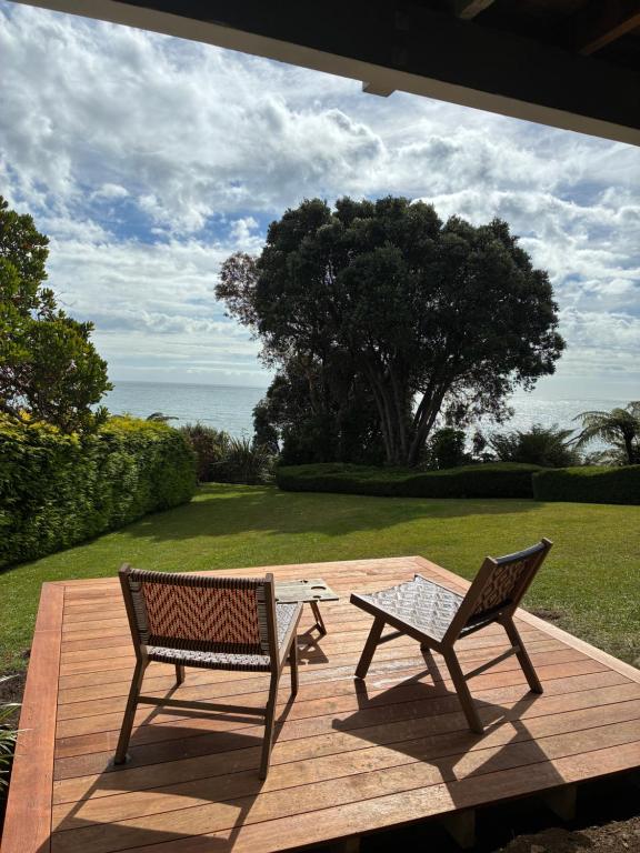 two chairs and a table on a wooden deck at Patons Rock Cutie in Rangihaeata
