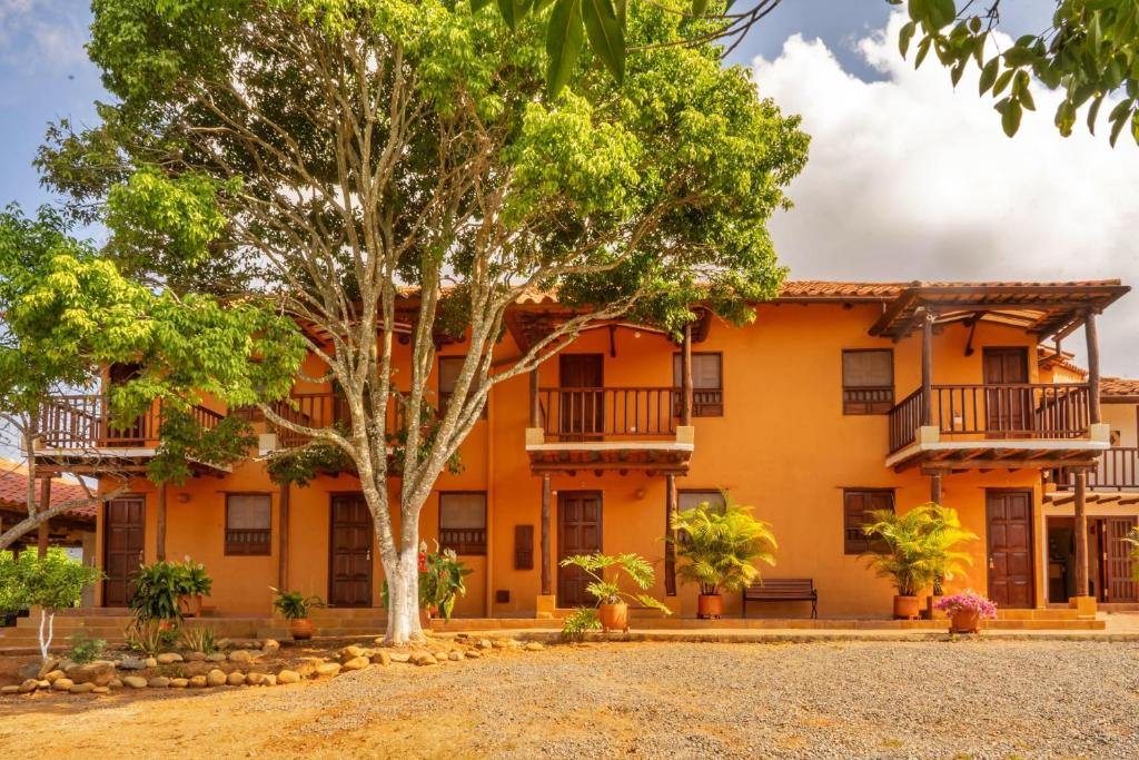 an orange building with trees in front of it at HotelQuintaMaria in Barichara
