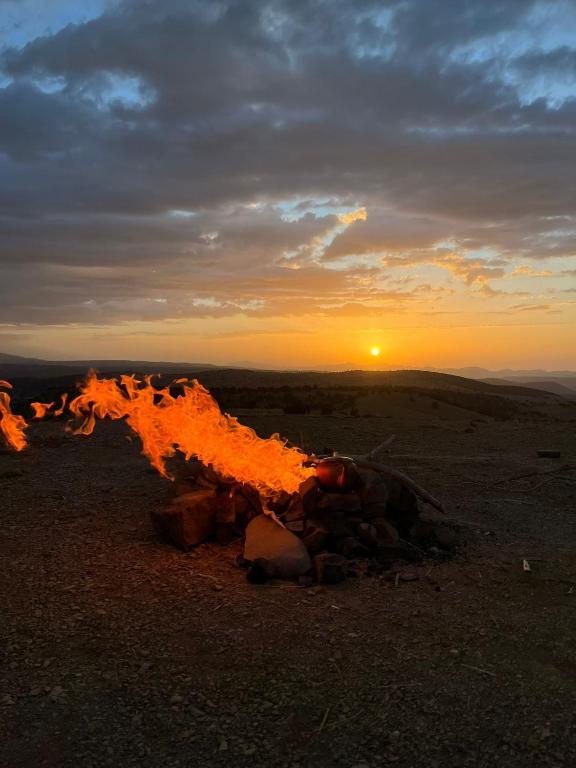 a fire pile in the desert with the sunset in the background at Gite Boutferda in Bou Tferda
