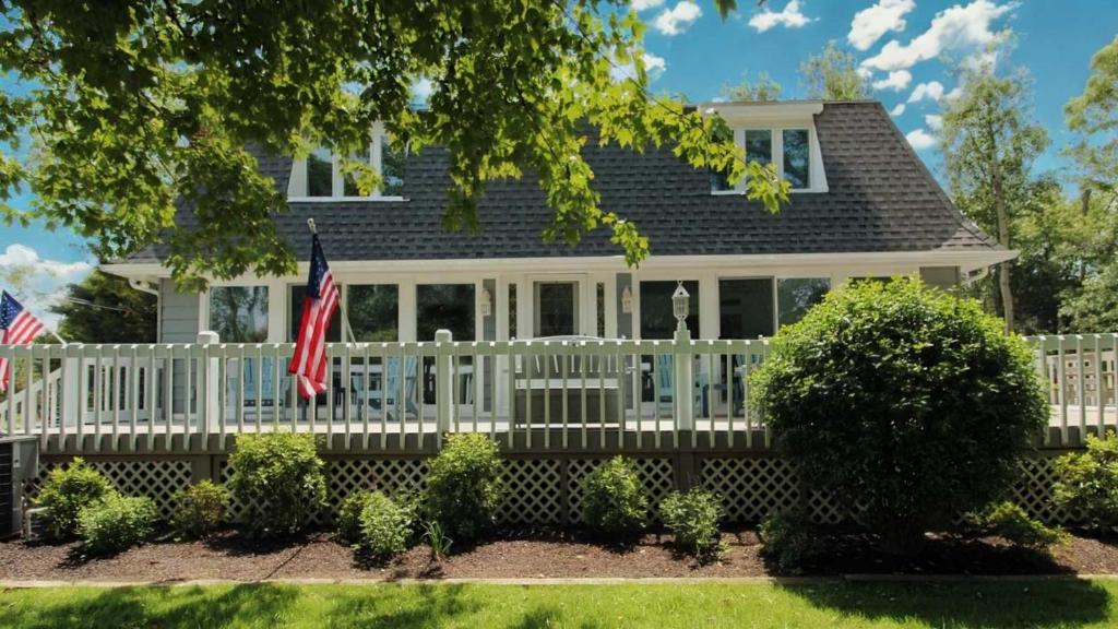 a house with a white porch and an american flag at 8 Bedrooms With A Pool - 404 Fourth Avenue in West Cape May