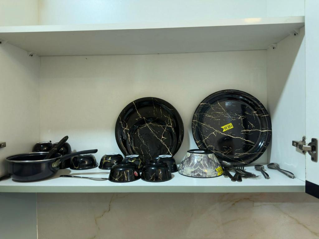 a shelf with plates and utensils on it at Luxury studios in Ghaziabad