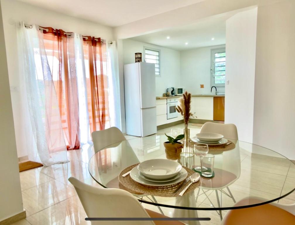 a dining room with a glass table and chairs at Appartement spacieux La Vanille 2 in Ducos