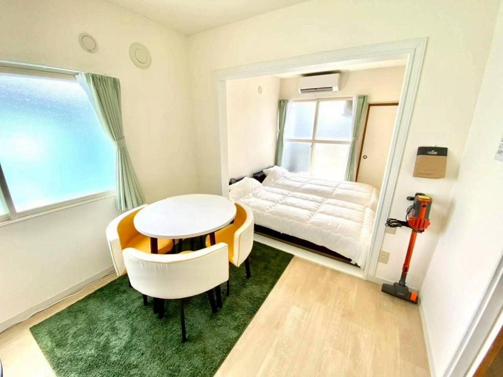 a small room with a bed and a table and chairs at LemonRooms in Aomori