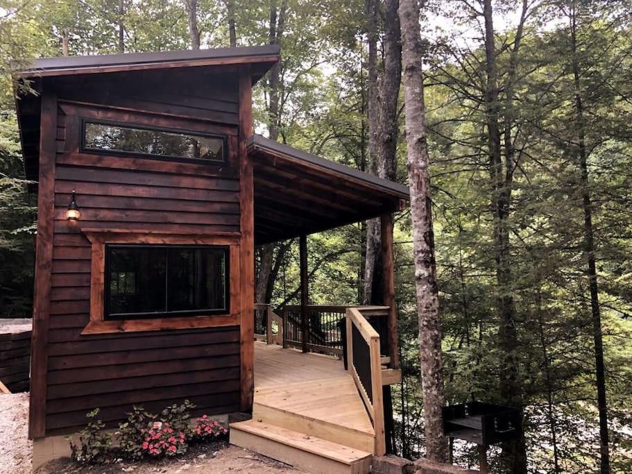 a small cabin in the woods with a deck at Theodore Tiny Cabin- RRG Hot Tub Pet Friendly in Slade