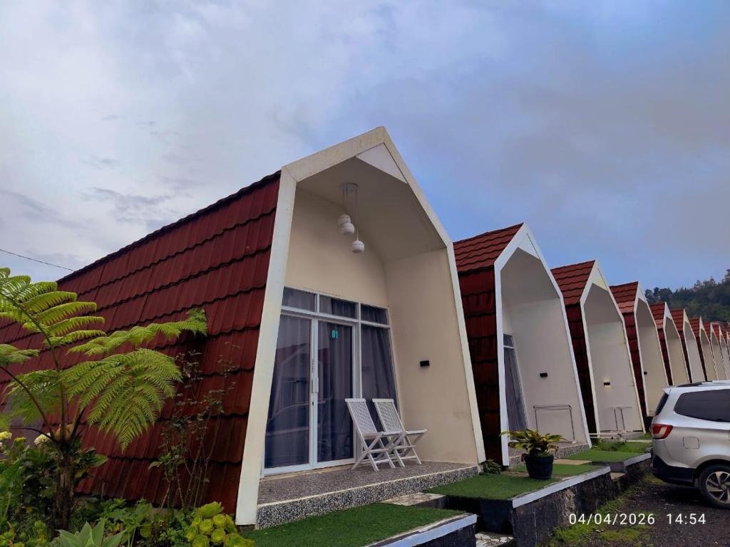a row of cottages with a car parked in front at Glamping Dieng New in Diyeng
