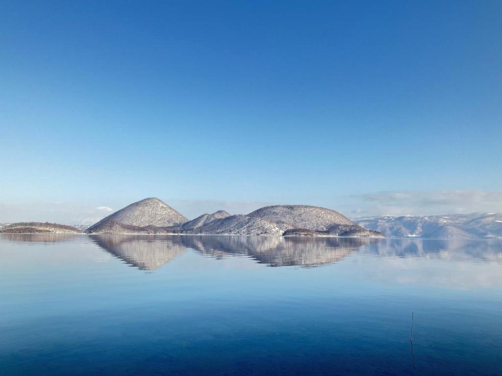 a view of a large body of water with mountains at Sauna Paistaa in Sobetsu