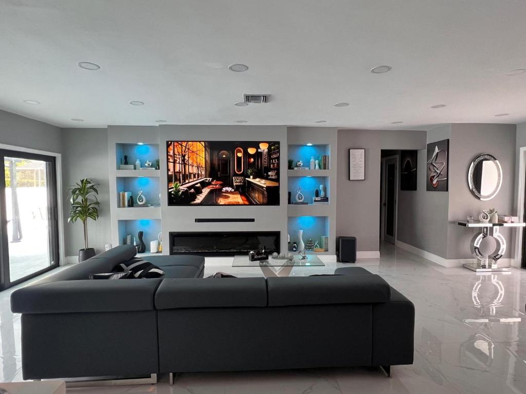 a living room with a large couch and a tv at Fun n Chic house with pool in Miami in Golden Glades
