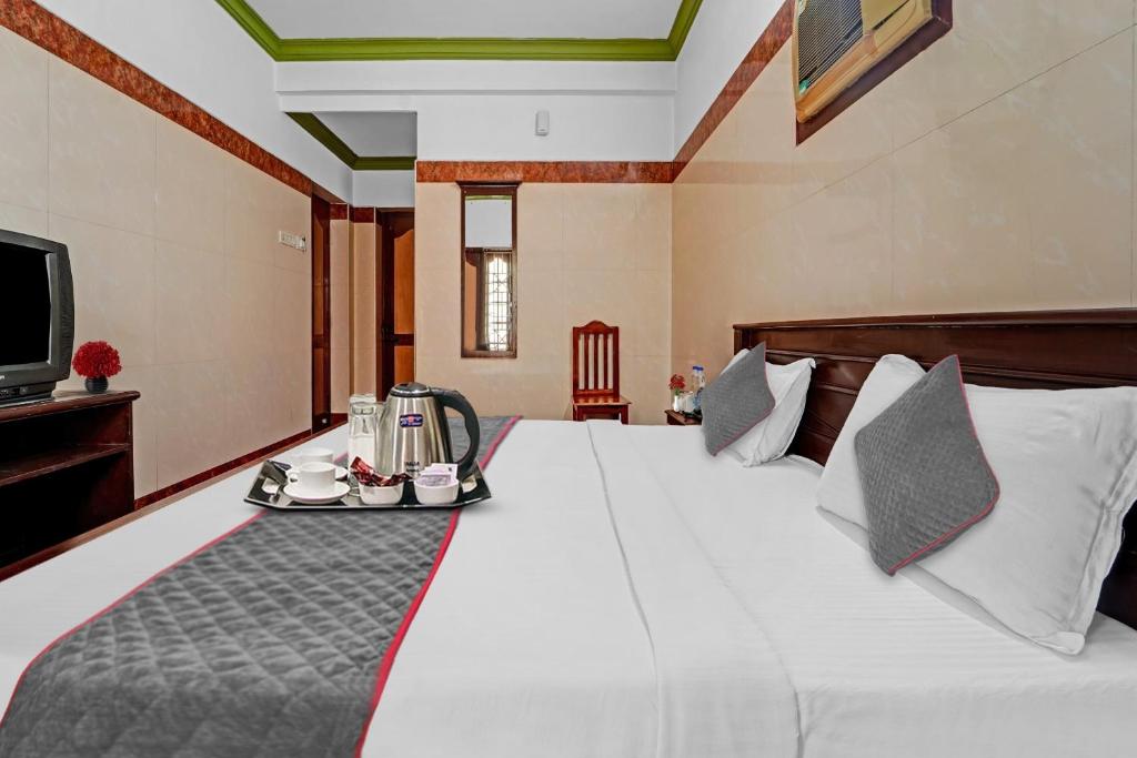 a hotel room with a bed with a tray on it at Hotel O Sasti Inn in Pondicherry