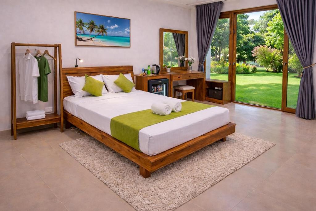 a bedroom with a large bed with a desk and a window at yashna villas in Pottuvil