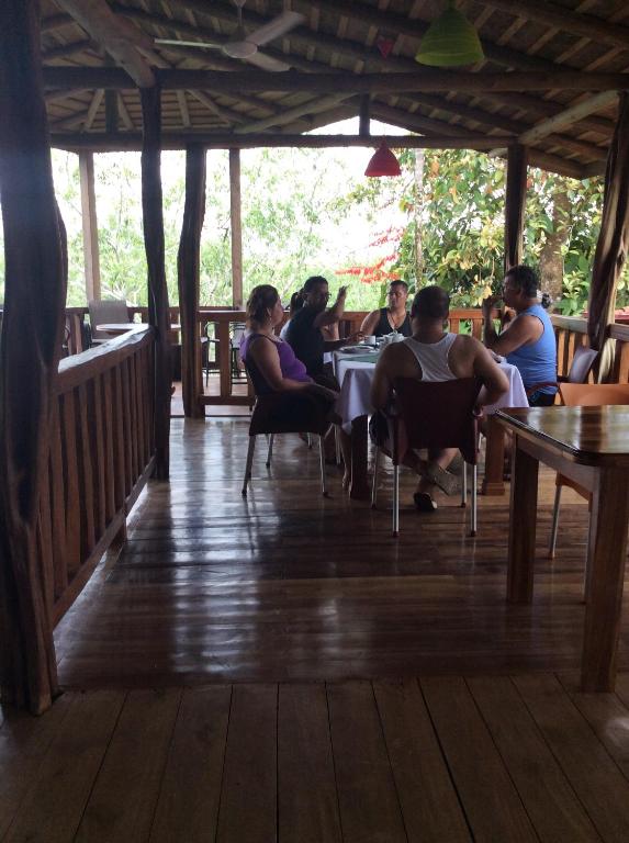 un grupo de personas sentadas en mesas en un restaurante en Hotel Pedacito de Cielo en Boca Tapada