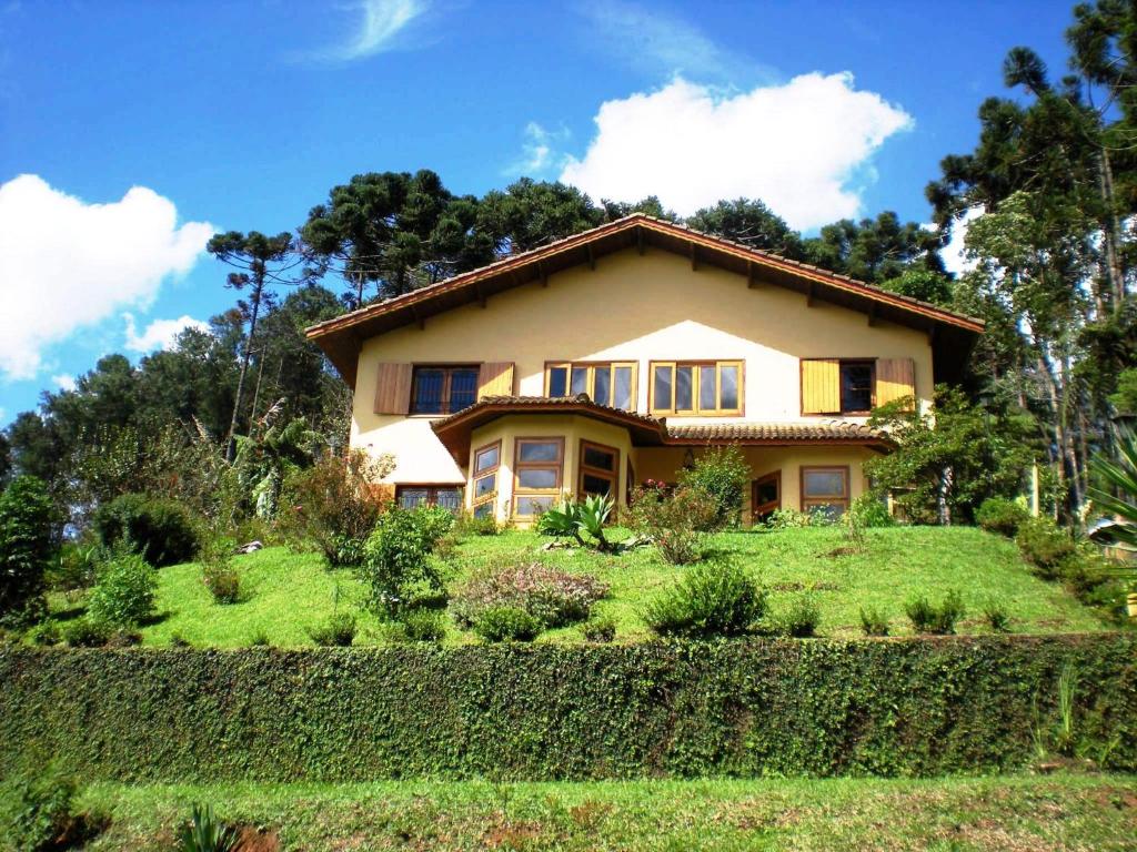 uma casa no topo de uma colina relvada em Refúgio do Azzi em Monte Verde