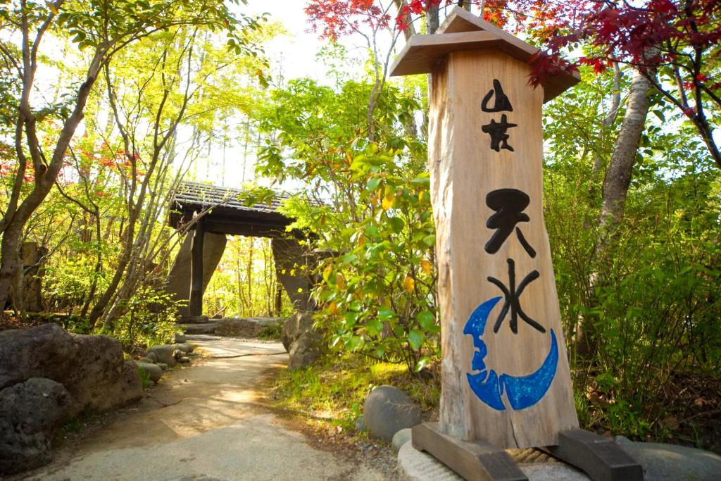 un poteau en bois avec des dessins à côté d'un sentier dans l'établissement Sanso Tensui, à Hita