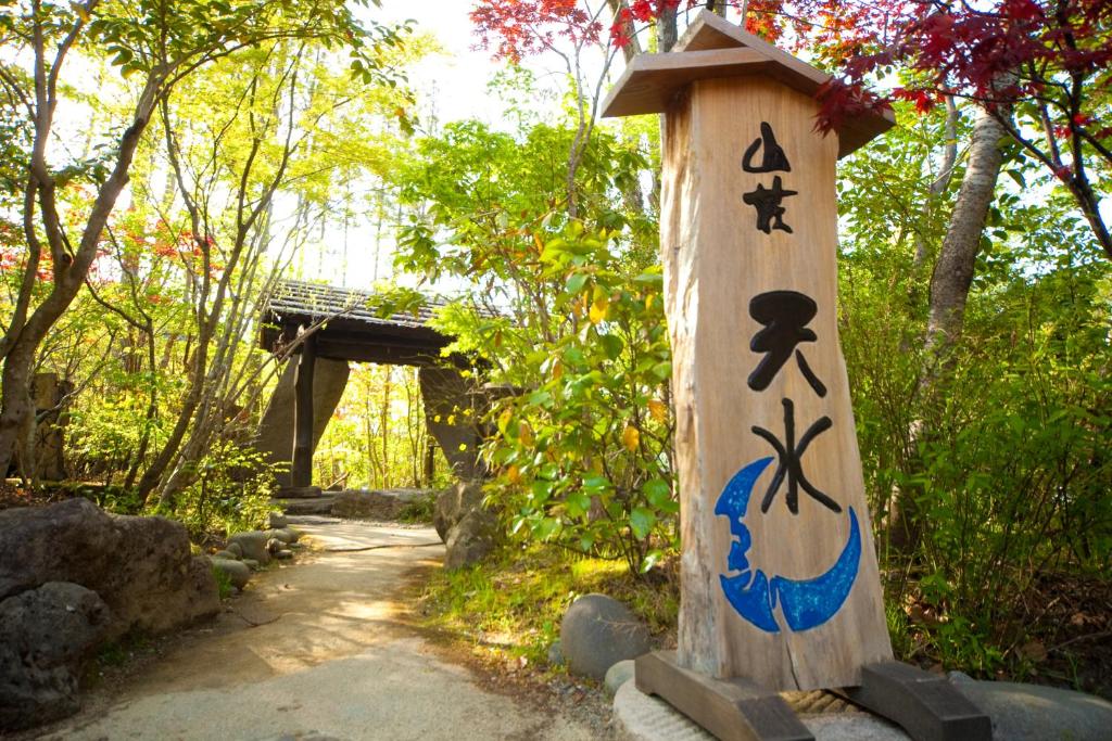 a wooden post with drawings on it next to a trail at Sanso Tensui in Hita