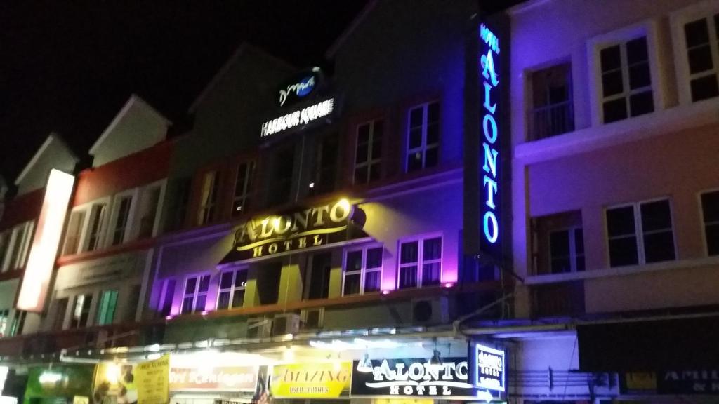 un edificio con un cartel de neón en él por la noche en Alonto Hotel, en Sandakan