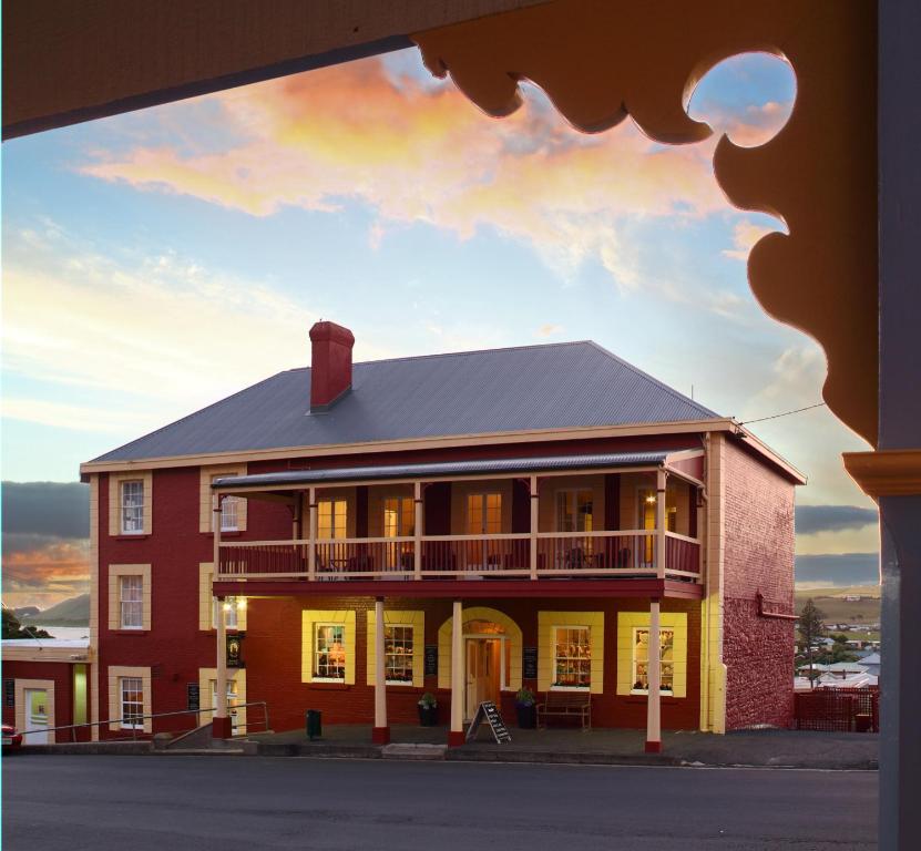 un grand bâtiment rouge avec un coucher de soleil en arrière-plan dans l'établissement Stanley Hotel & Apartments, à Stanley