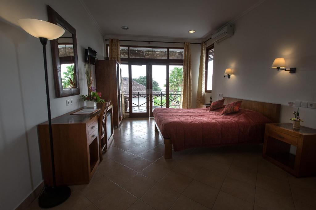a bedroom with a bed and a dresser and a window at Ecosfera Hotel & Spa in Canggu