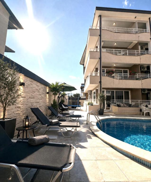 a swimming pool with lounge chairs and a building at Complex Yavor in Aheloy