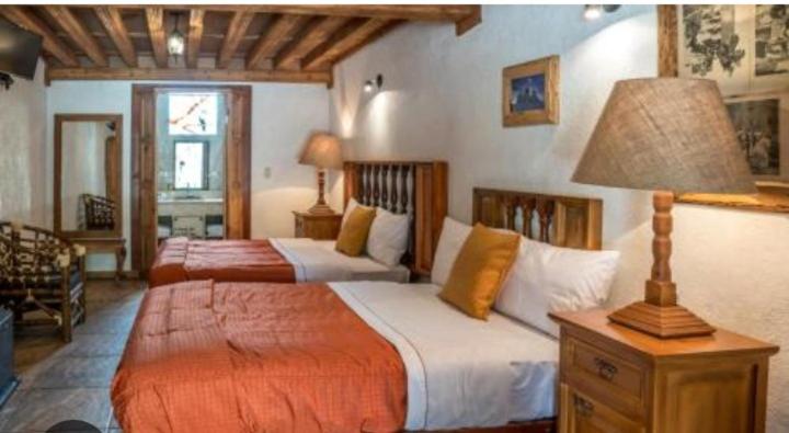 a bedroom with two beds and a table with a lamp at Un poco de paz in Puebla