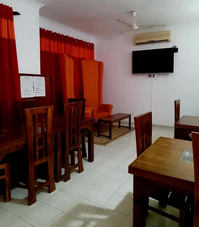 a dining room with tables and chairs and a flat screen tv at Thambili lk in Colombo