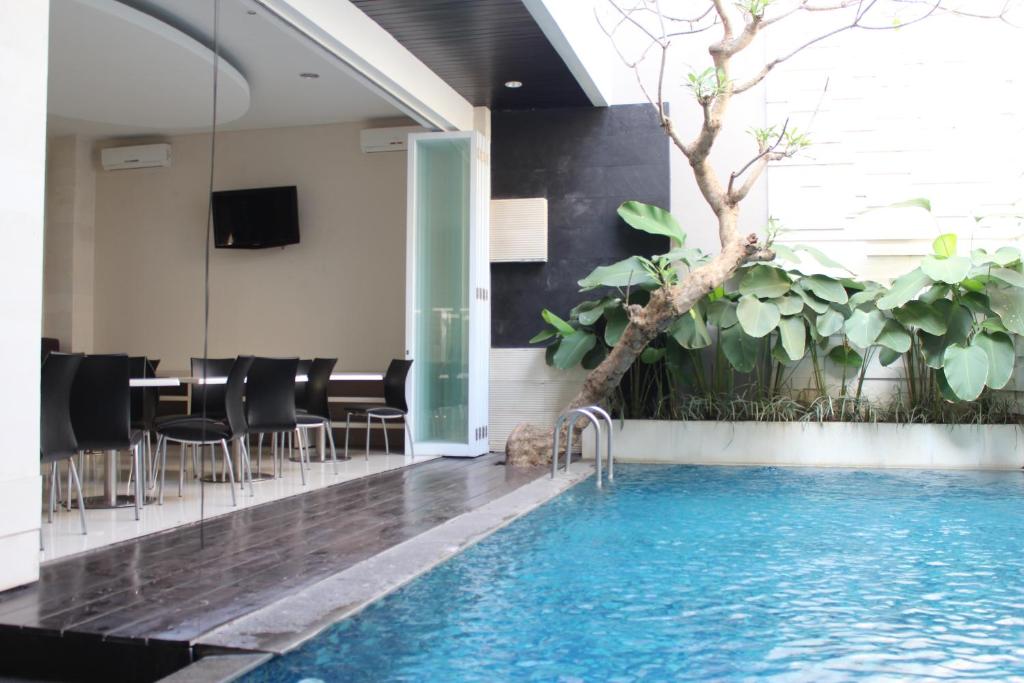 a swimming pool in a room with a table and chairs at InKuta Residence and Villa in Seminyak