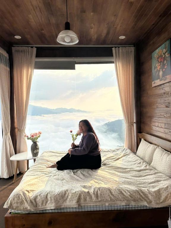 a woman sitting on a bed in front of a window at Trúc house in Kon Rung (1)
