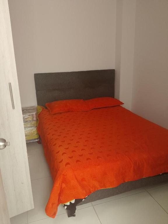 a bed with an orange comforter in a room at Edificio Karu in Pamplona