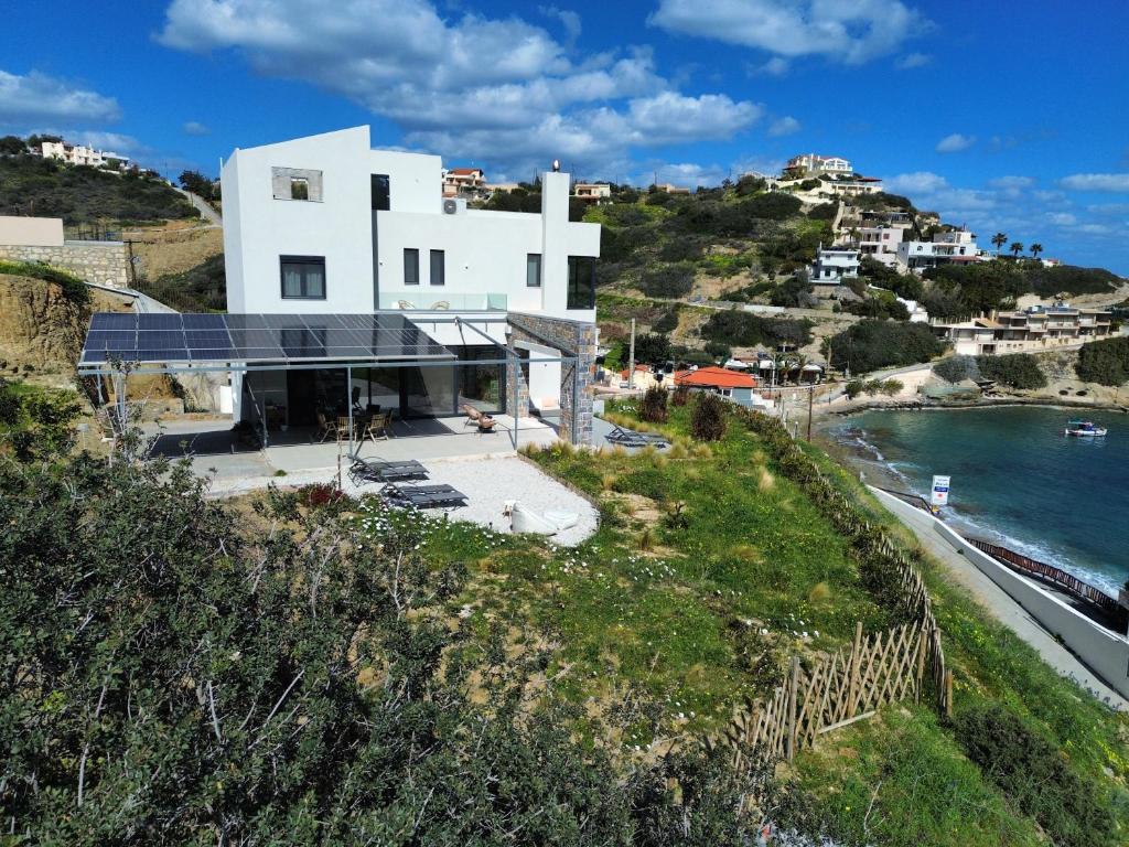 a white house on a hill next to the ocean at Theasea beachfront luxury residence in Ligaria