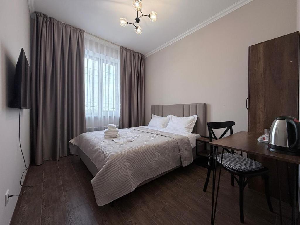 a hotel room with a bed and a desk with a television at Orion Hotel in Almaty