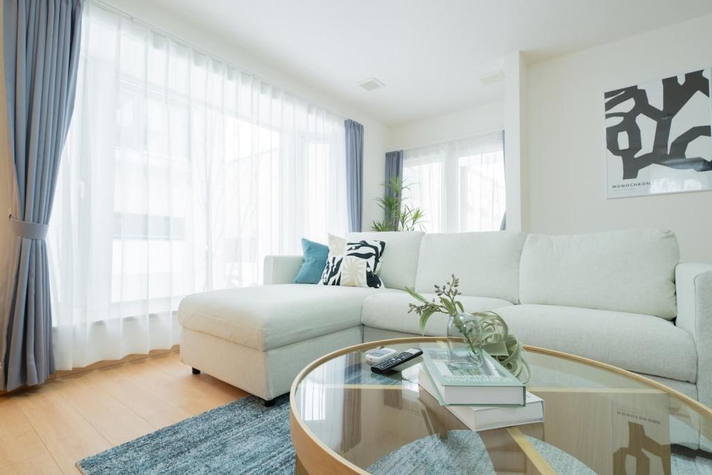 a living room with a couch and a glass table at Asahikawa Kawabata House in Asahikawa