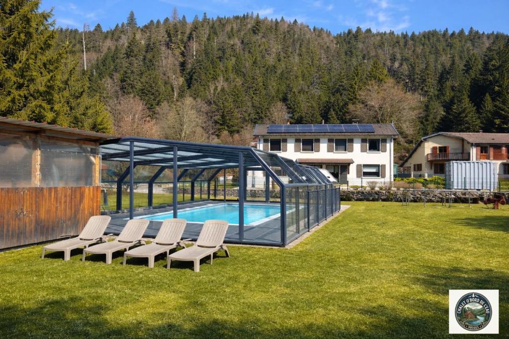 a swimming pool with chairs and a glass house at Chalet Lodge - O'Bord de l'Eau in Gérardmer