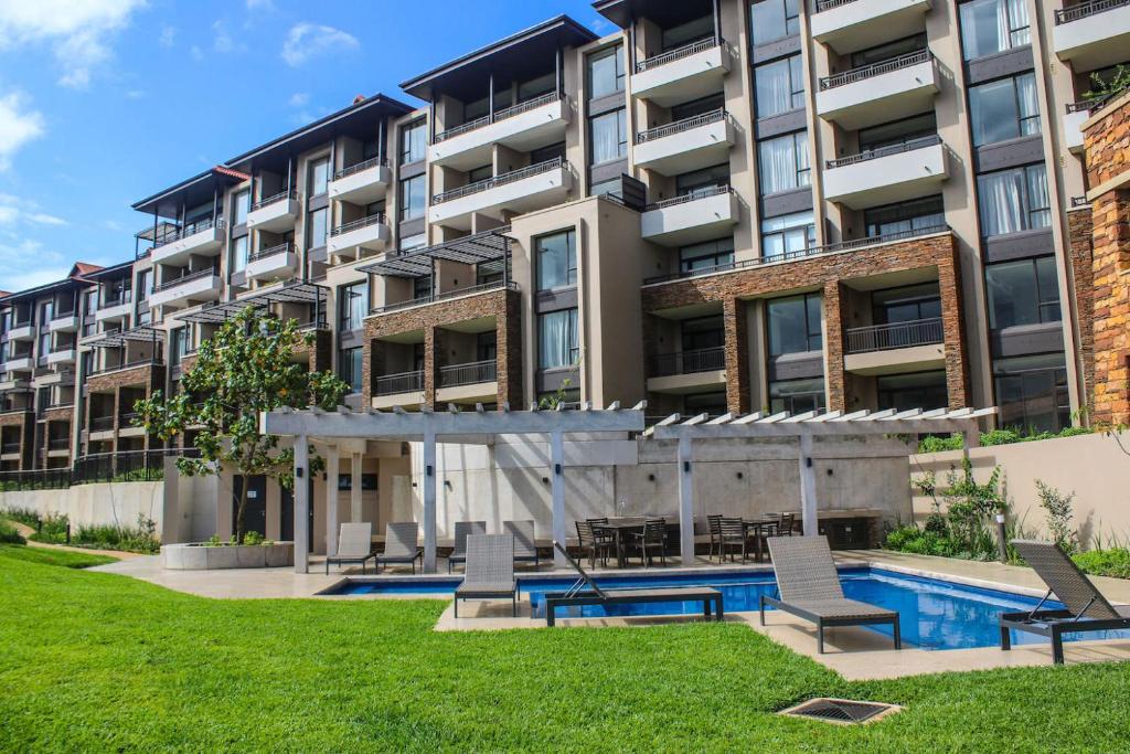 an apartment building with a swimming pool and chairs at 204 Zimbali Suites in Ballito