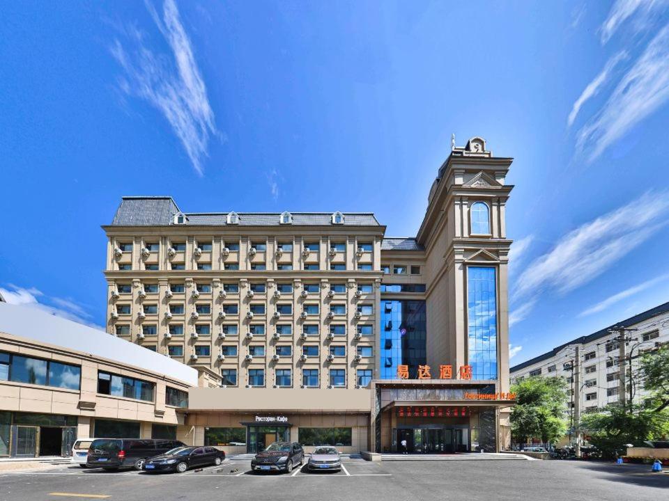 a large building with cars parked in a parking lot at 黑河易达酒店 in Heihe