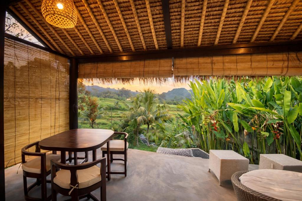 a patio with a table and chairs and a large window at The Kubu Sidemen in Silebeng