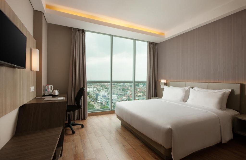 Postel nebo postele na pokoji v ubytování Hotel Santika Radial Palembang