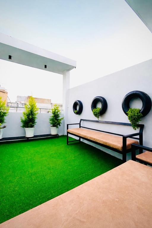 a living room with a bench and green grass at Nexaura Stays in Indore