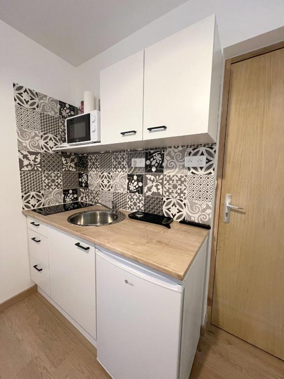 a kitchen with white cabinets and a sink at Studio 2 Résidence Eugénie in Eaux-Bonnes