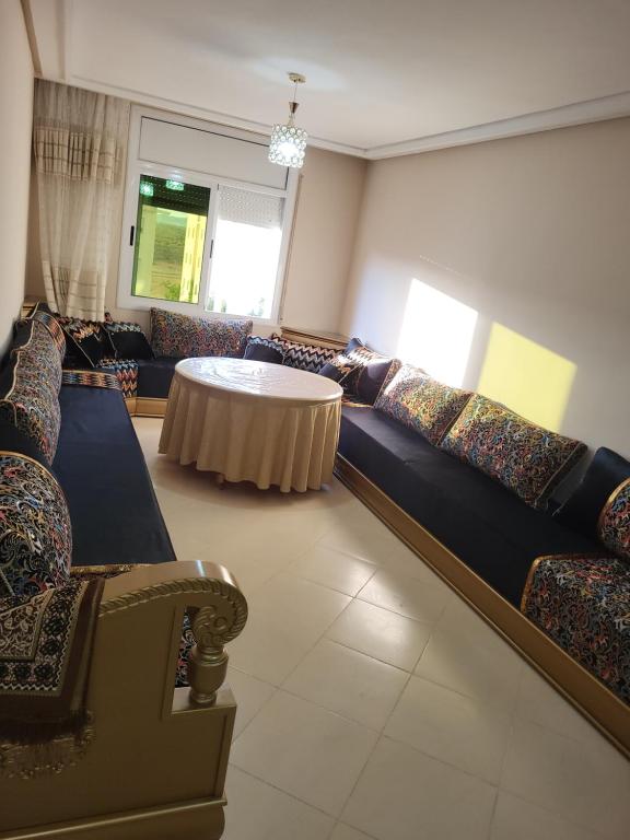 a living room with couches and a table in it at appartement NADOR wifi gratuit clima mobile in Selouane