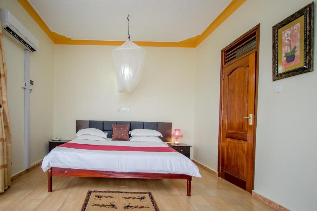 een slaapkamer met een bed en een kroonluchter bij Askay Hotel Suites in Entebbe