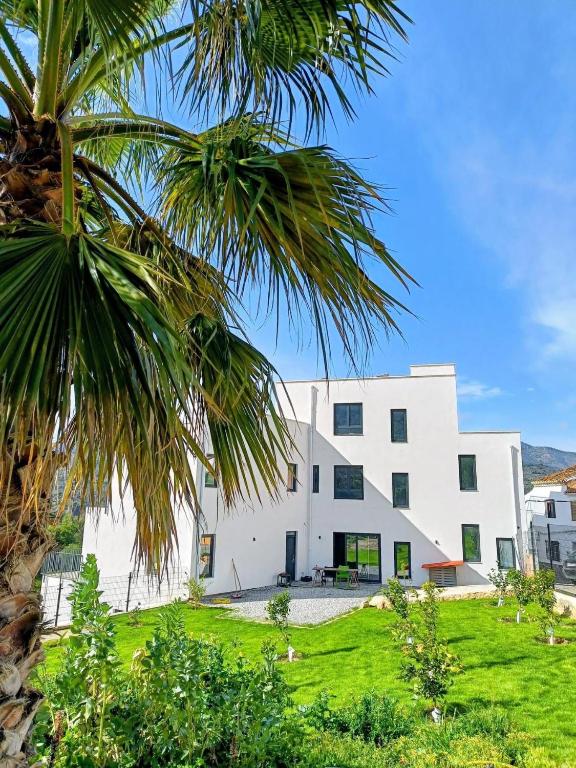 a white building with a palm tree in front of it at Casa la Perla Solo adultos in Béznar