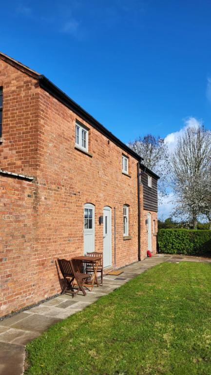 a brick building with a picnic table in front of it at Gardeners Cottage Apartment in Tyberton