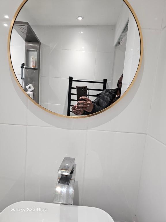 a man taking a picture of a mirror in a bathroom at Emmanuel INN XI in Pierrefitte-sur-Seine