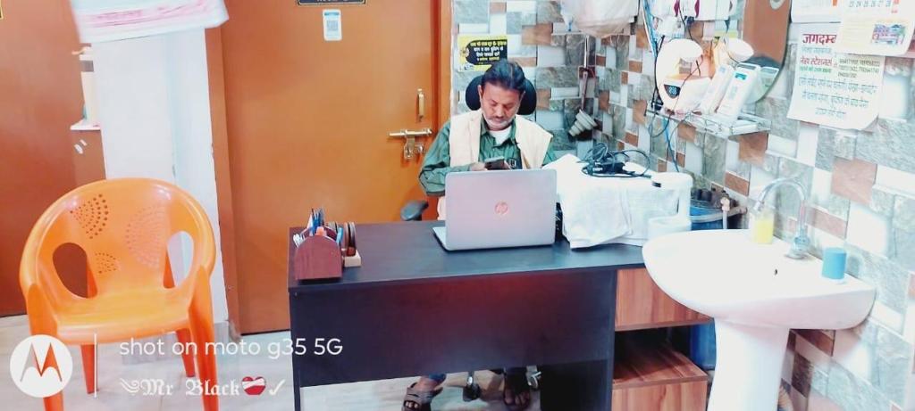 a woman sitting at a desk in a bathroom with a laptop at Jagdamba home stay in Ayodhya