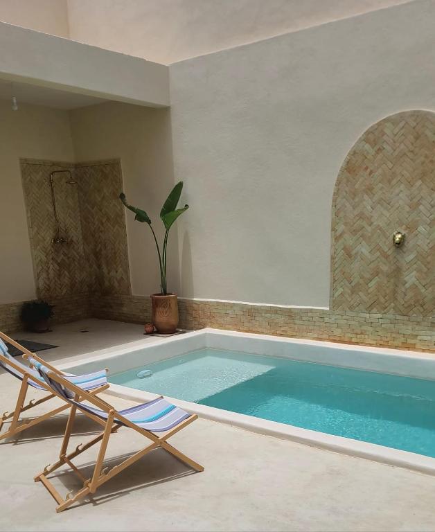 a swimming pool with a lounge chair and a chair at Ryad Fnina in Tiznit