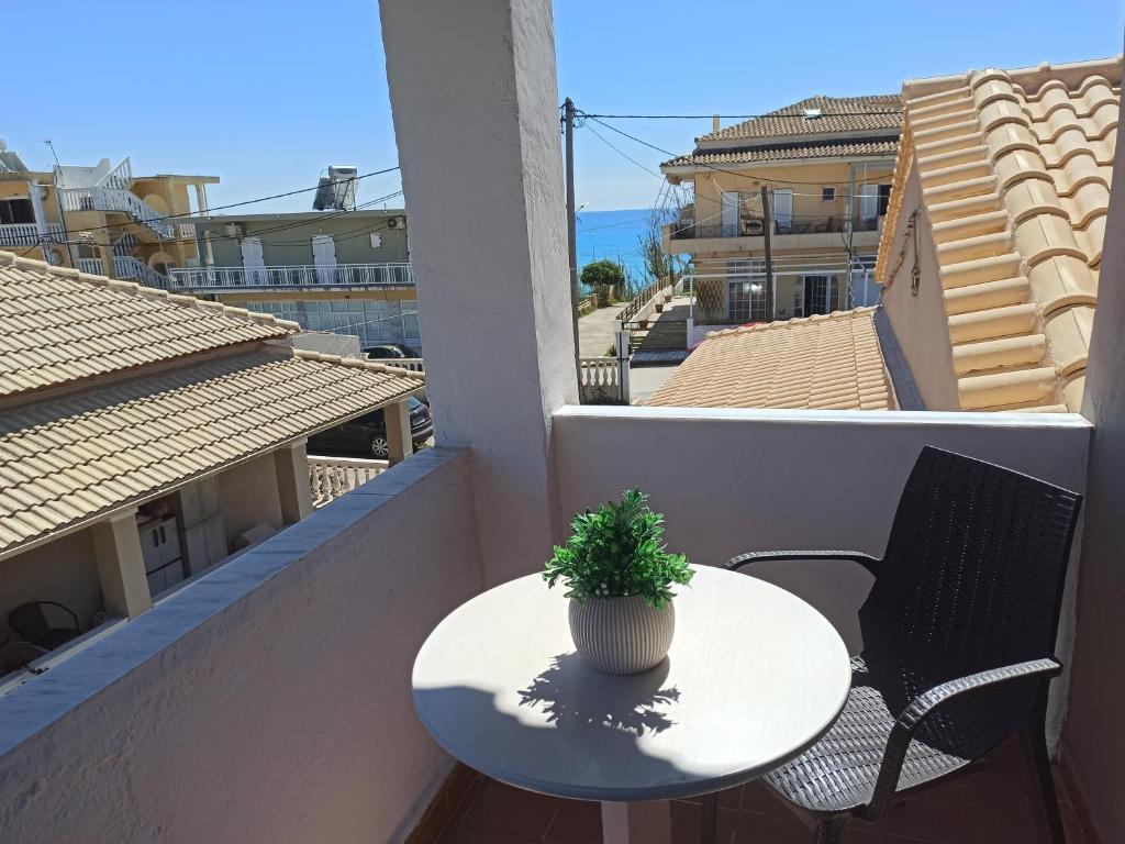 a table and chairs on a balcony with a plant at Christodoulos Apartment in Agios Georgios