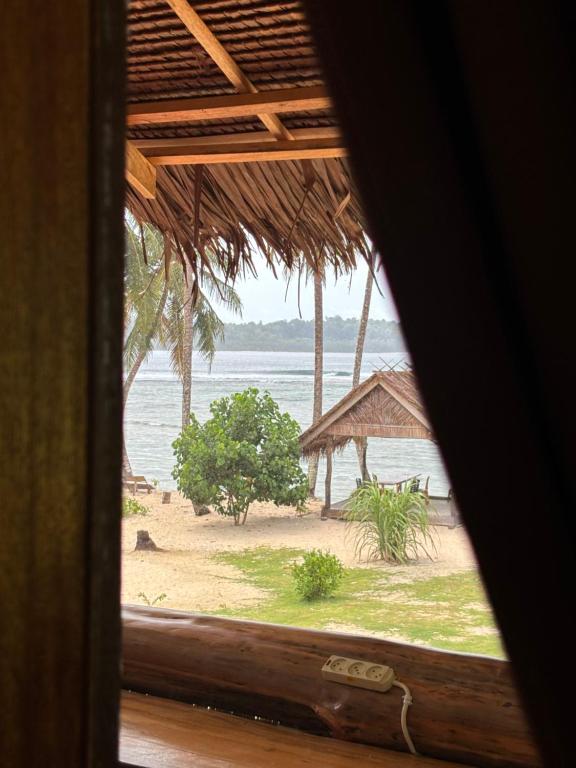 a view of a beach from a window at Onaza Homestay Bintang in Katiet